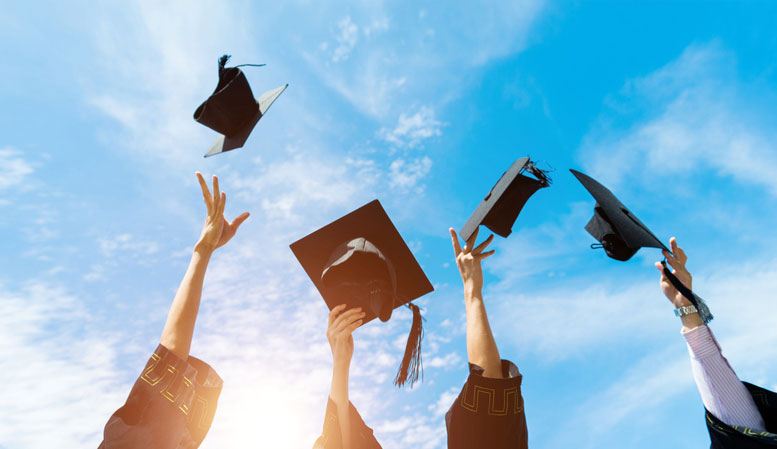 graduates celebrating by throwing their caps into the air