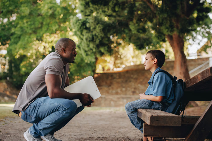 mentor talking with young man on bench