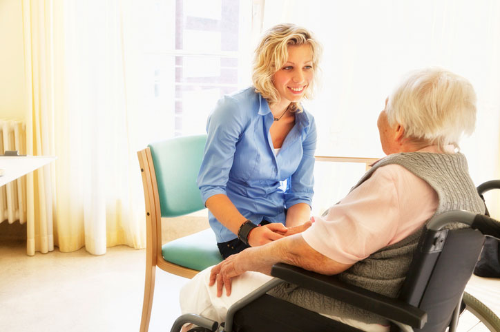 elderly woman in wheelchair talking with healthcare social worker