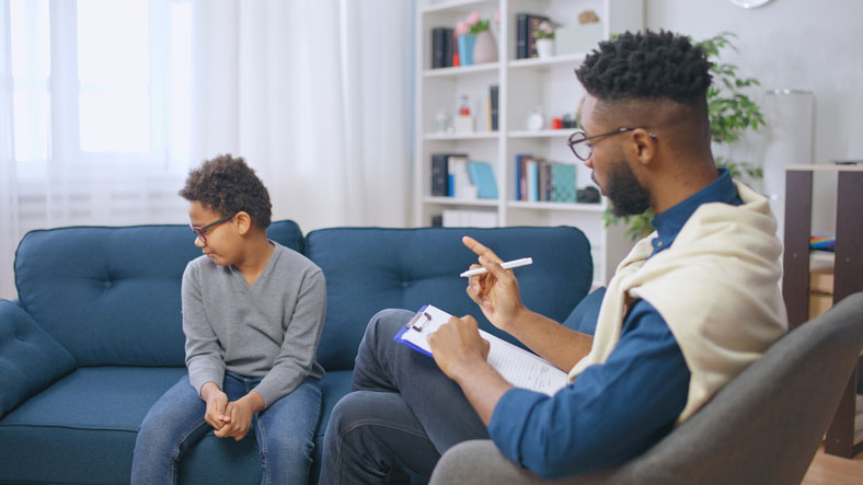 social worker talking with young boy on couch