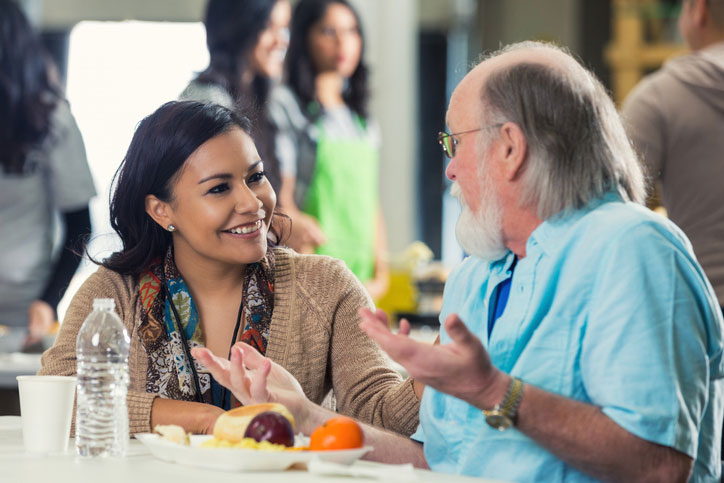 social worker talking with homeless man during lunch