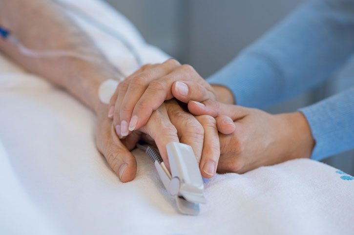 healthcare worker holding onto hands of patient