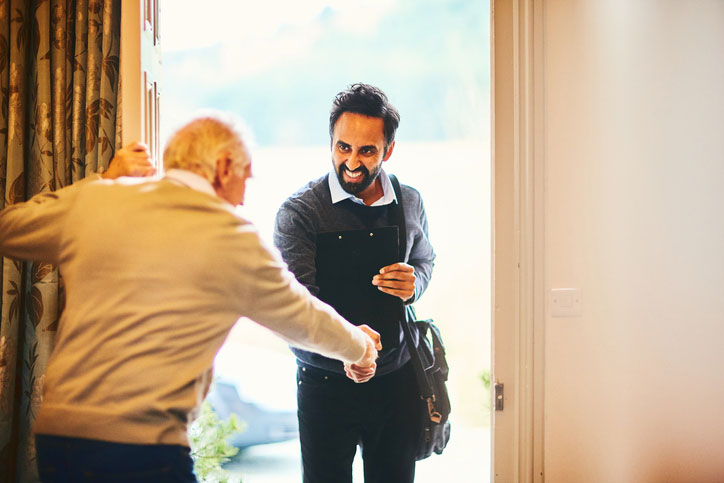 senior man answering door for social worker